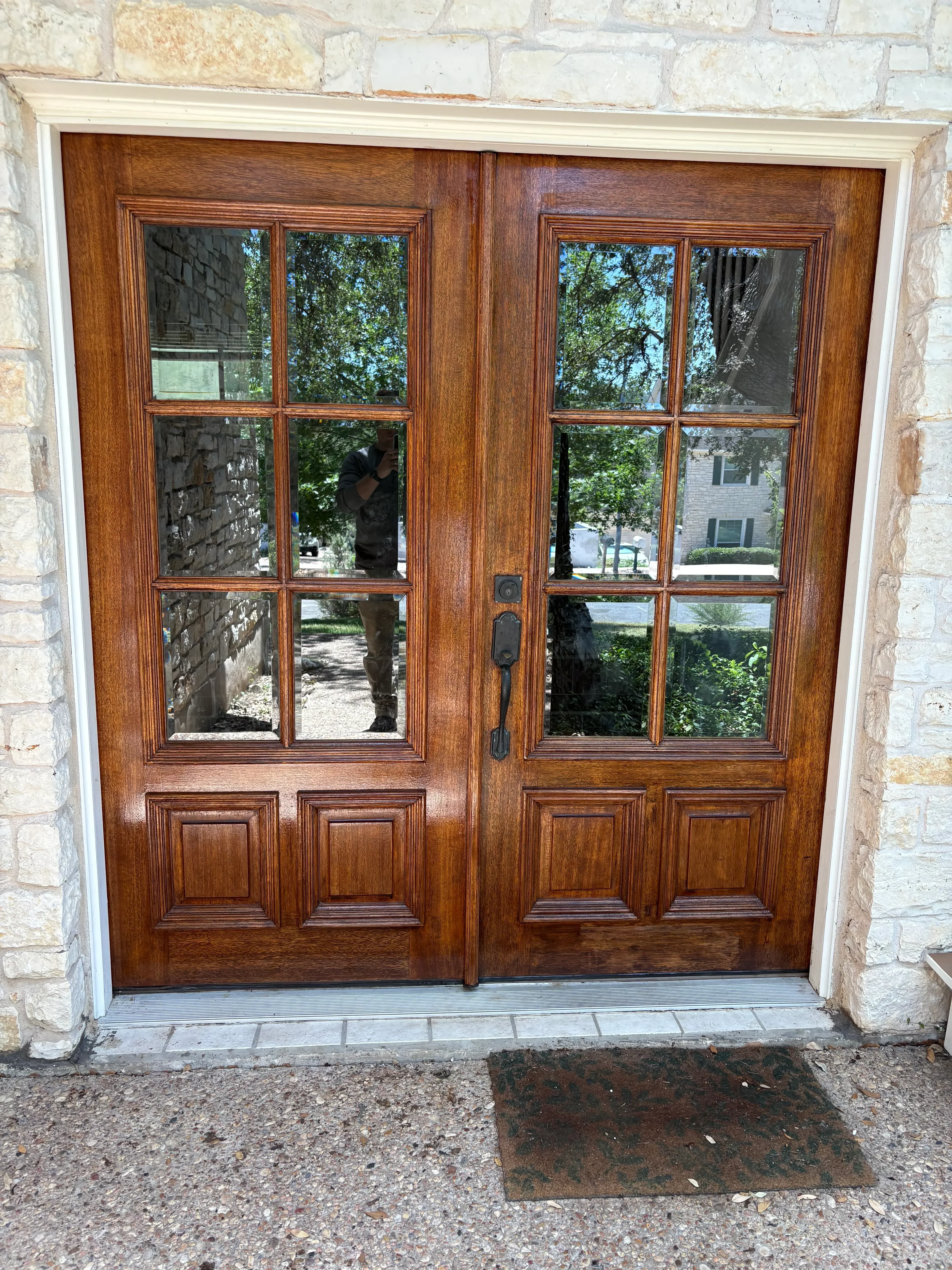 Wooden garage door with six-panel glass inserts and stained finish on stone facade