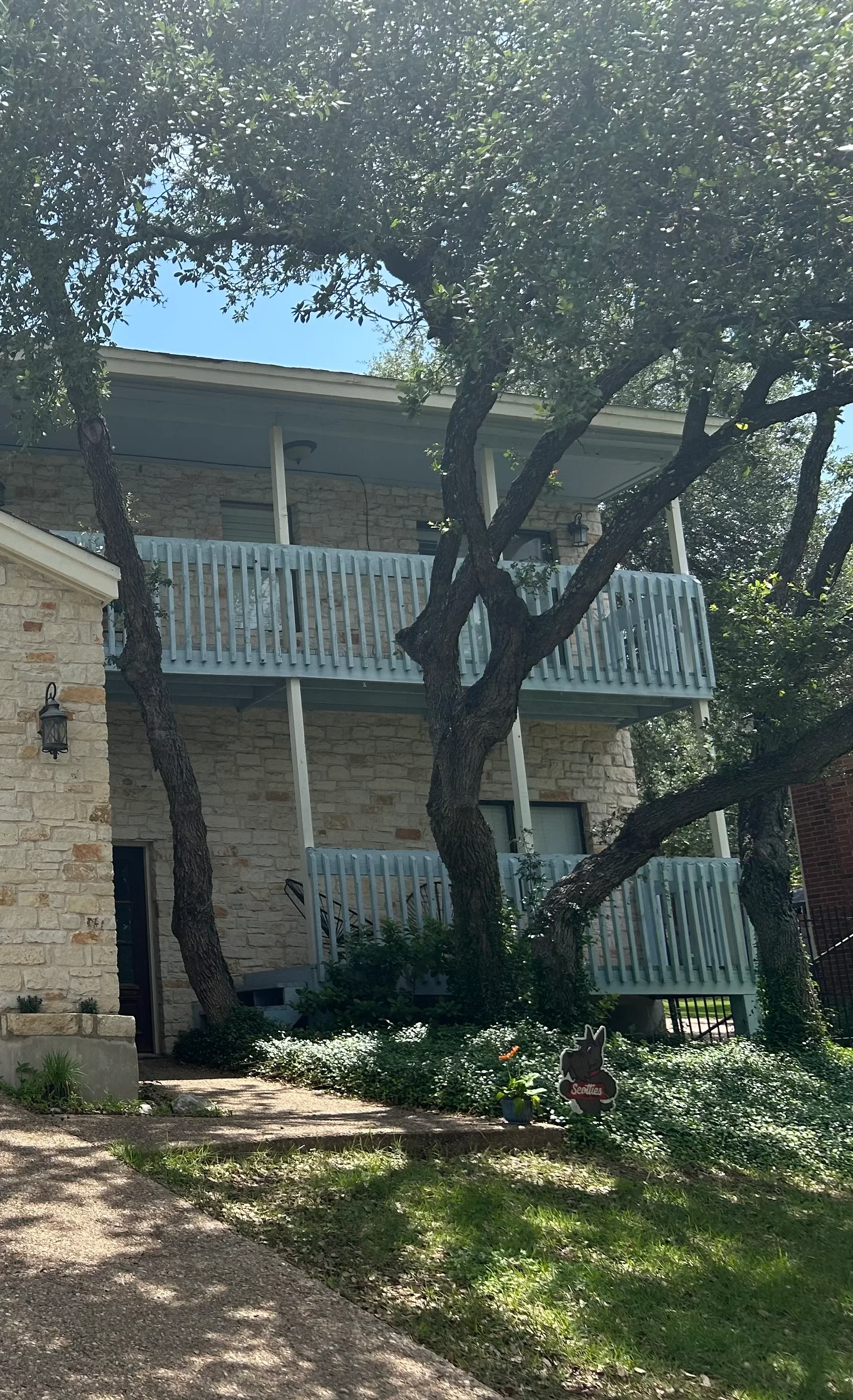 Two-story stone house with white painted deck railings and freshly painted exterior siding