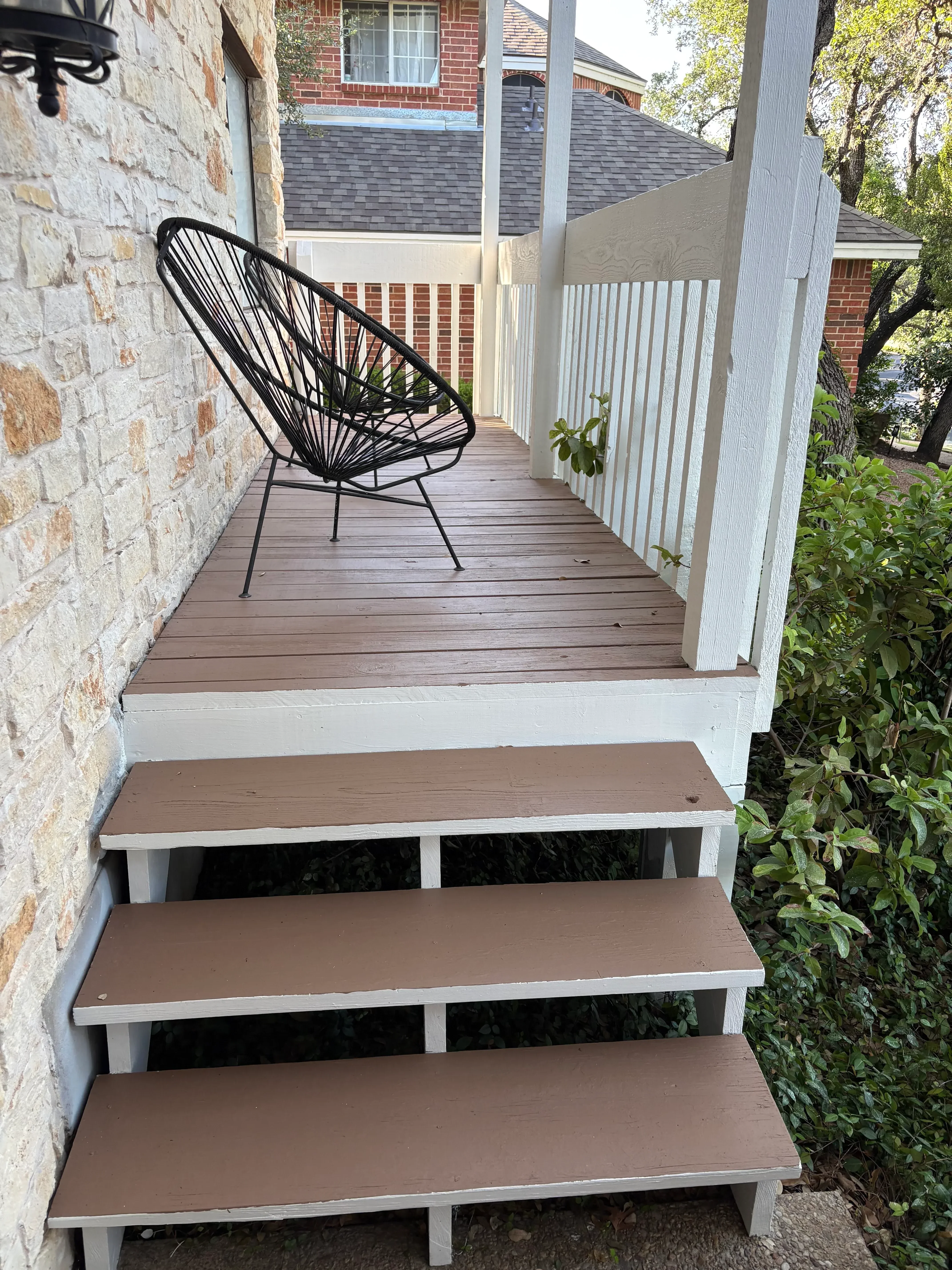 White pergola with horizontal slats and taupe wood privacy screens on stone patio