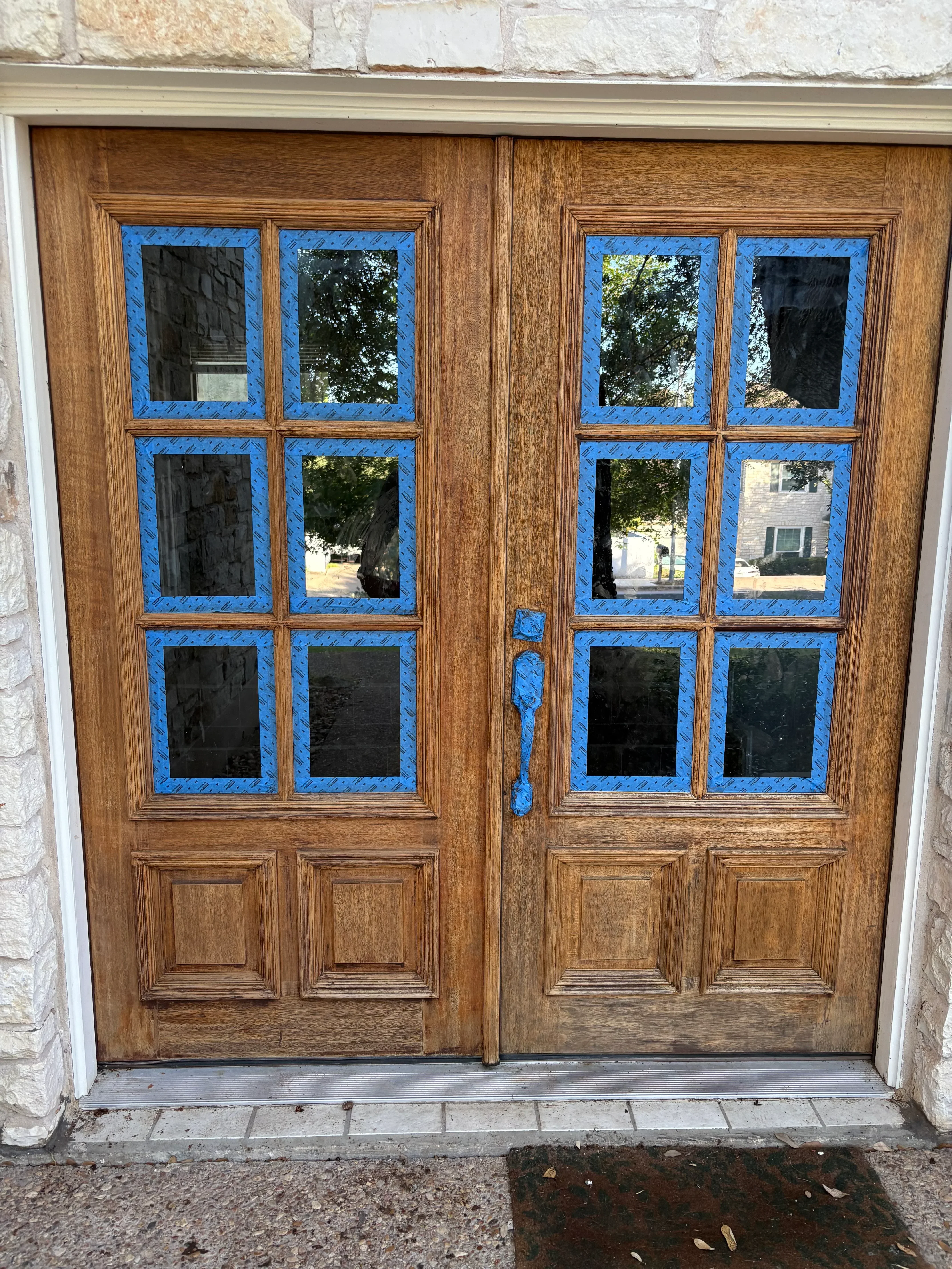 Wooden garage door with six glass panels and blue trim accents on wood frame