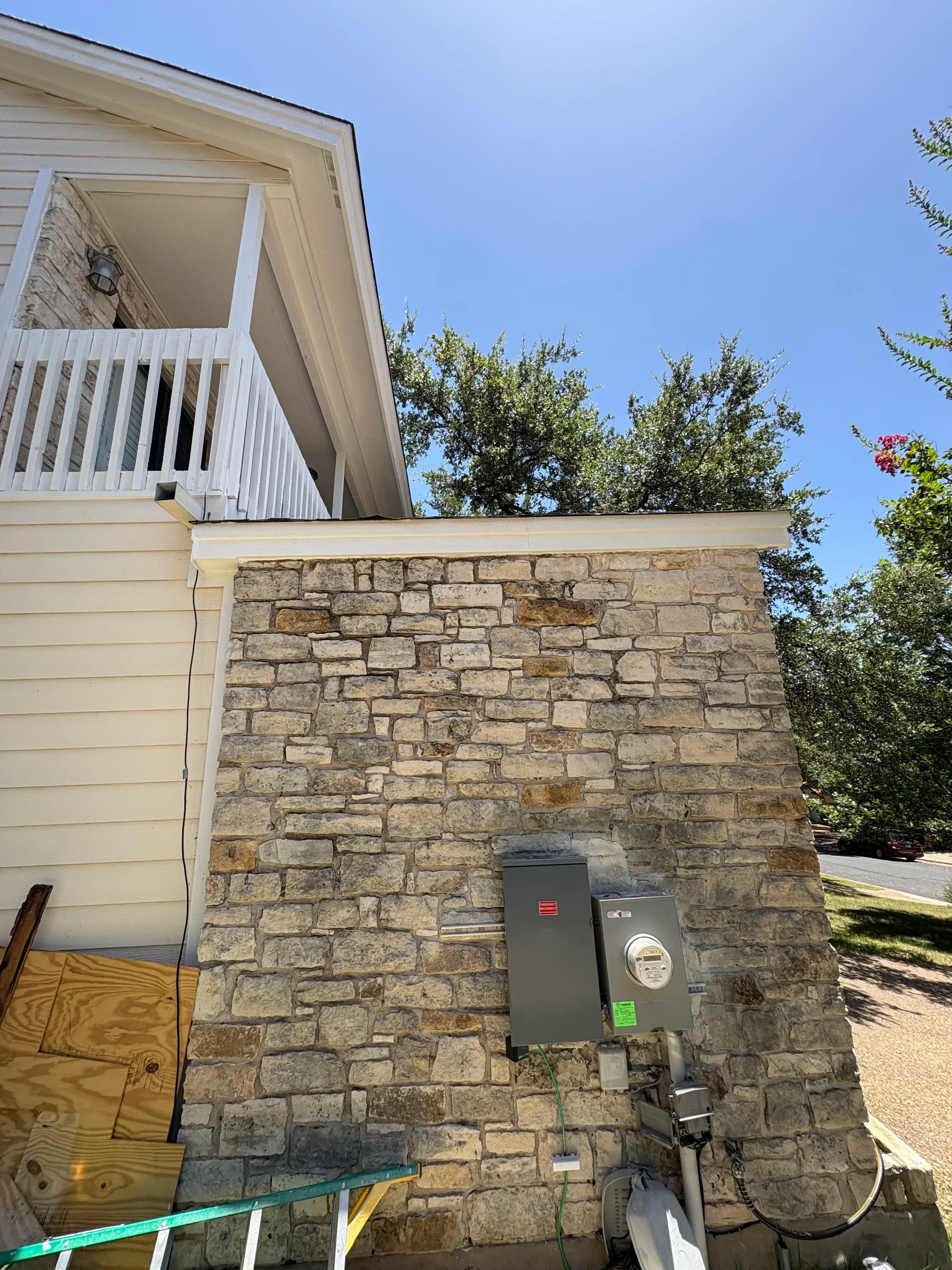 Stone veneer exterior wall with fresh paint application and electrical fixtures