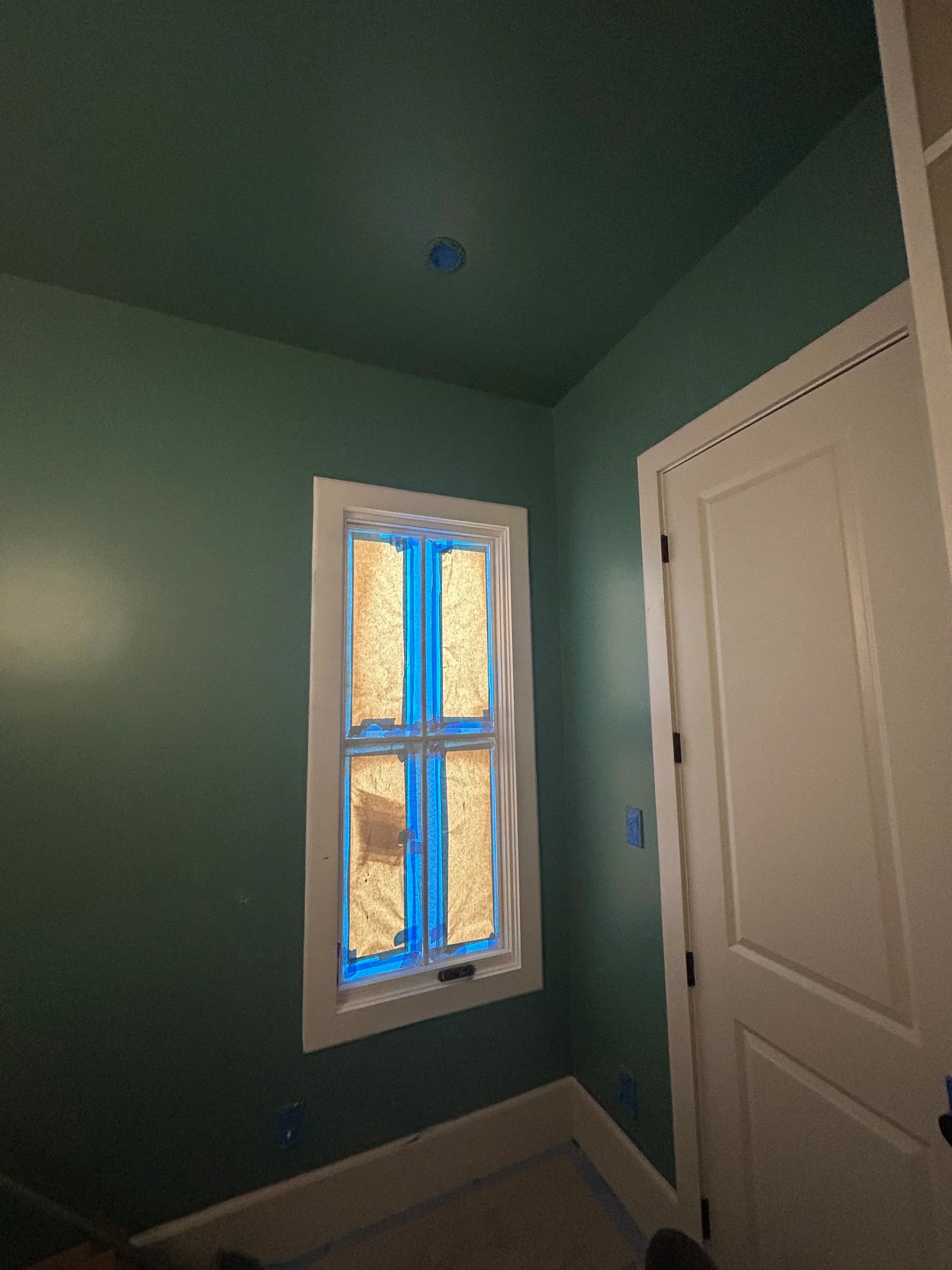 Sage green drywall walls with white coffered ceiling trim and four-pane window frame