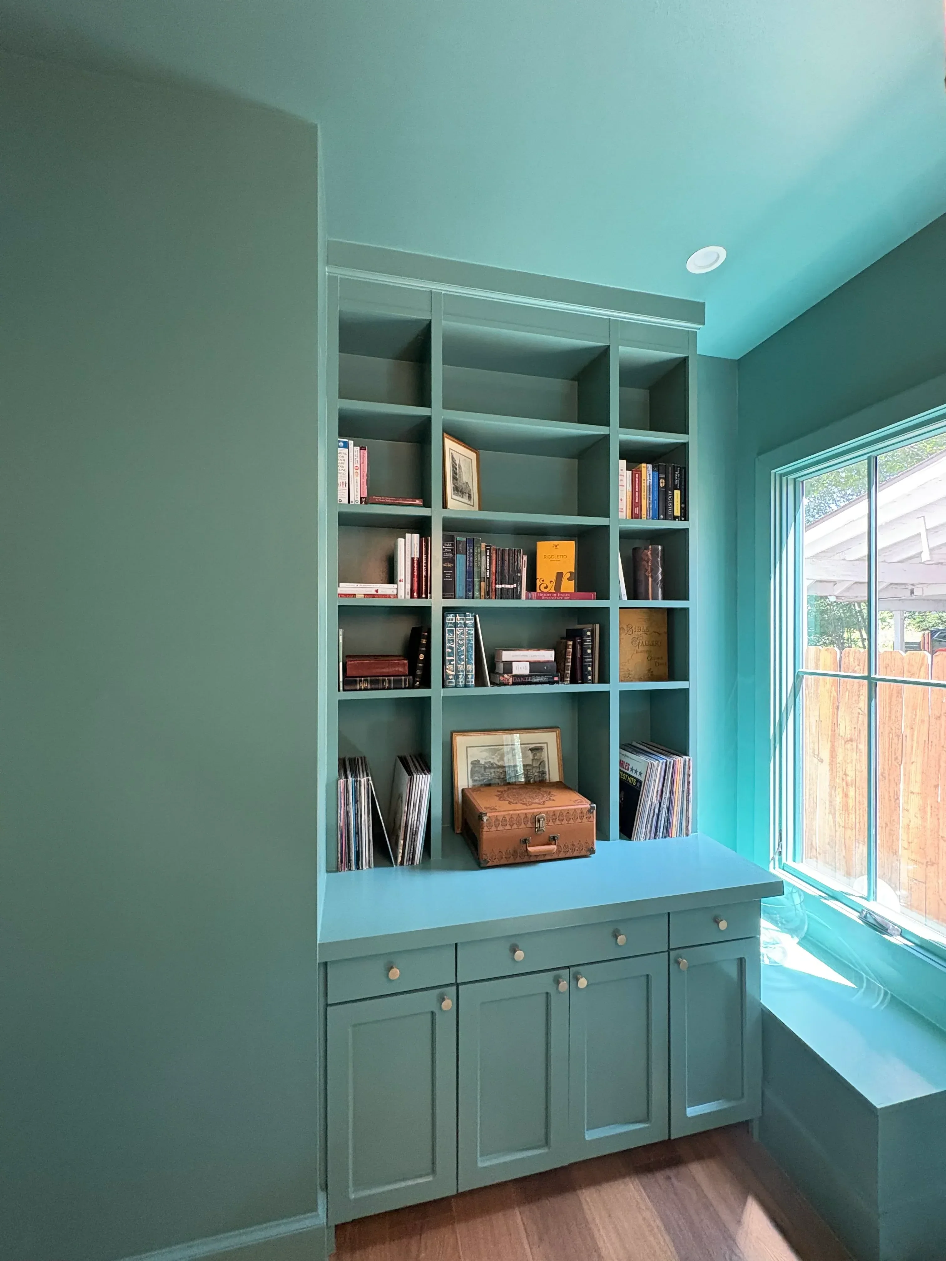 Turquoise painted accent wall with built-in shelving, skylight, and matching painted cabinet doors