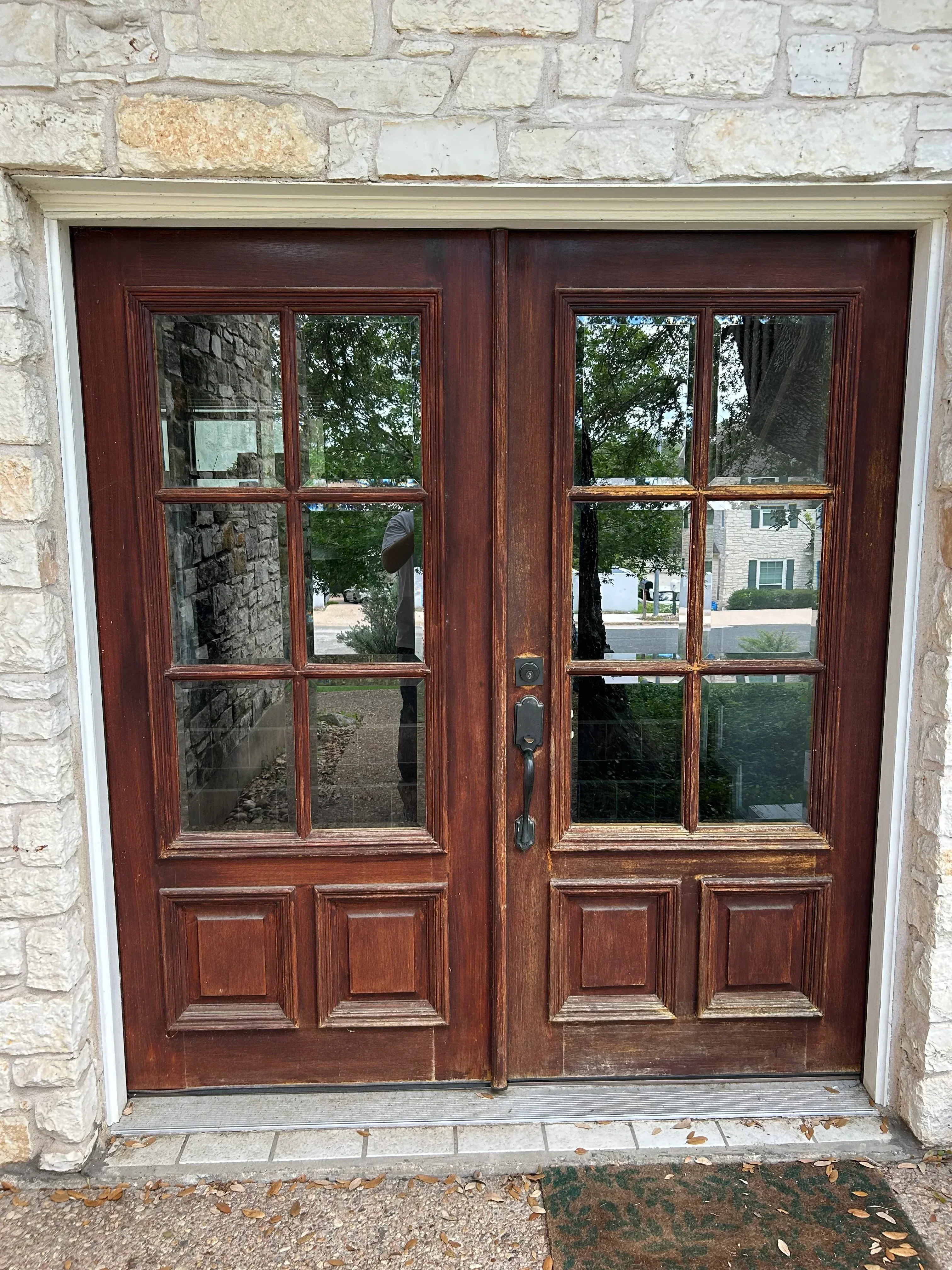 Mahogany-stained wooden garage door with glass and panel sections, stone surround