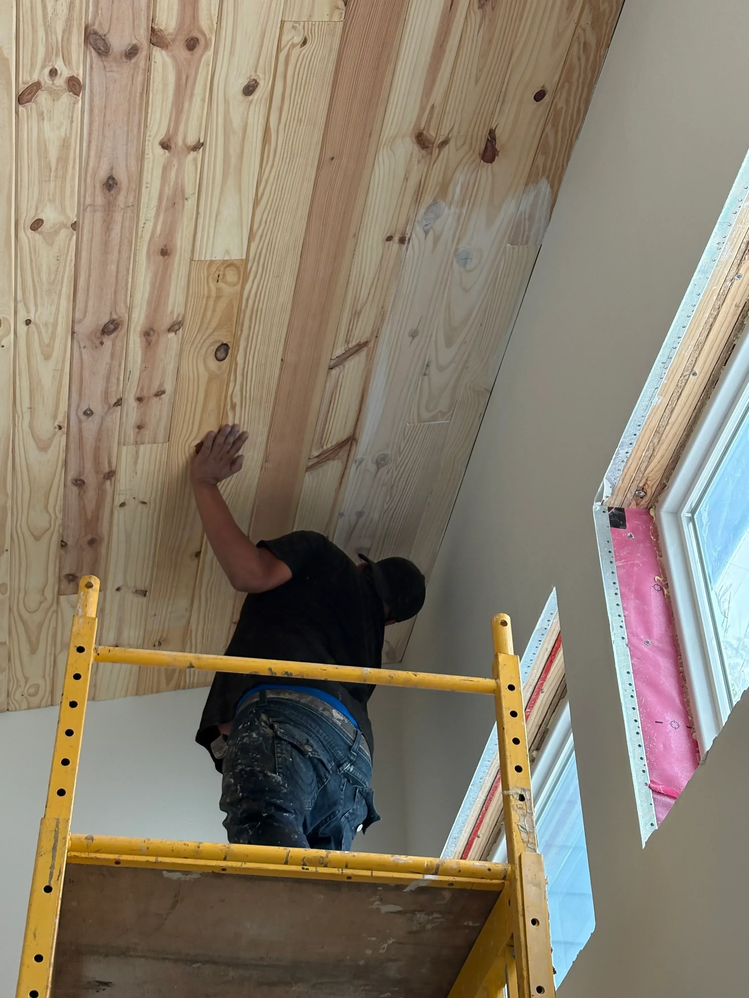 Interior painting with skylights, wood shiplap walls, and protective vapor barriers during installation